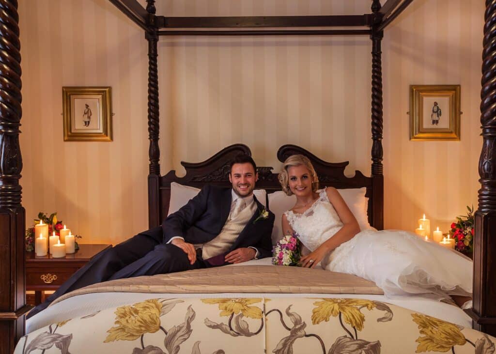 Bride and Groom sitting together on a beautiful four poster bed