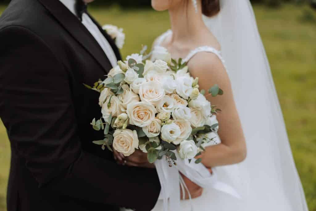 Bride and groom holding one another outdoors with flowers