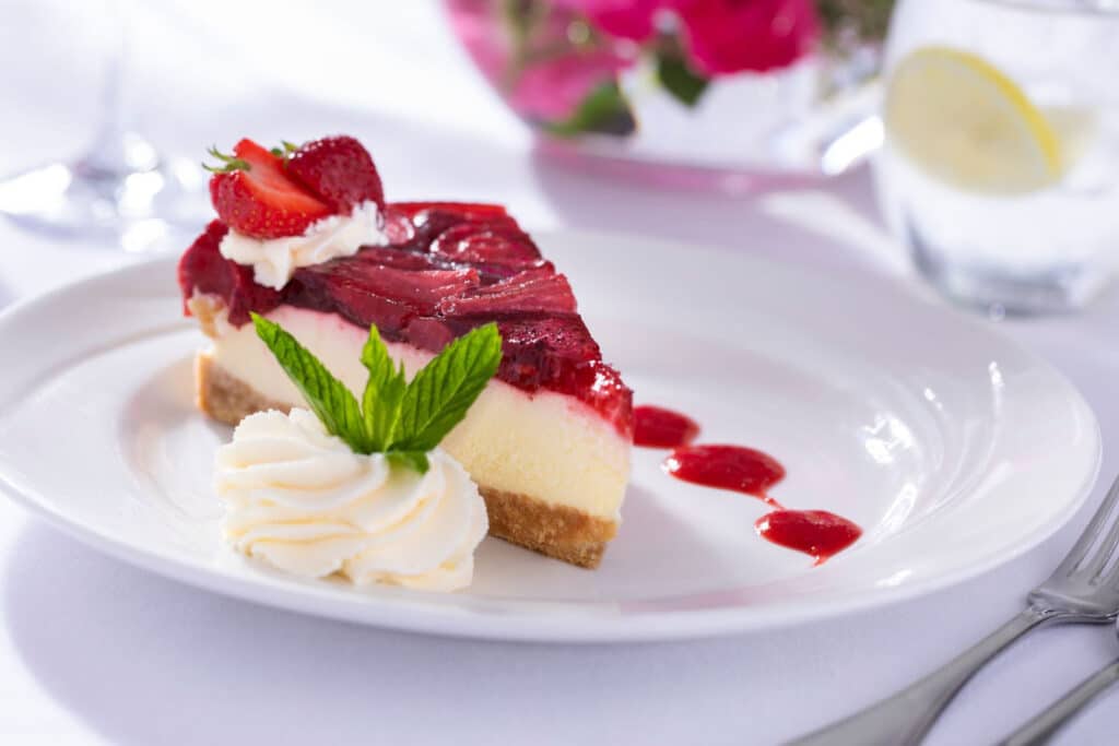 Close up view of strawberry cheese cake with fresh cream on the side