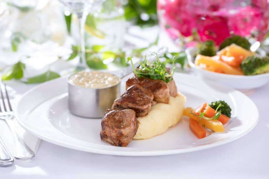 Meat dish on a bed of mashed potatoes with few carrots