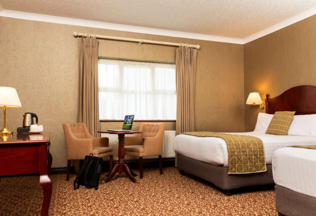 View of bedroom with laptop on the desk and a bag on the floor