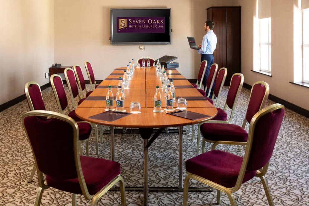 View of conference room from the back of the room with man facing towards the screen