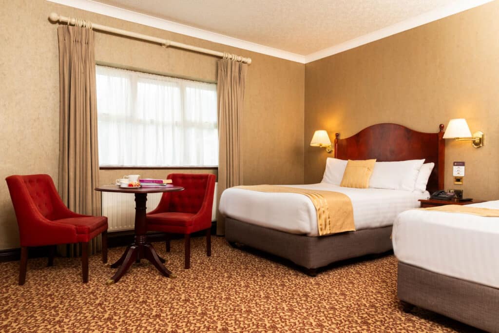 View of double bed with desk and chairs beside