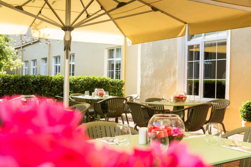 View of outside terrace of tables and pink flower in shot at the seven oaks hotel