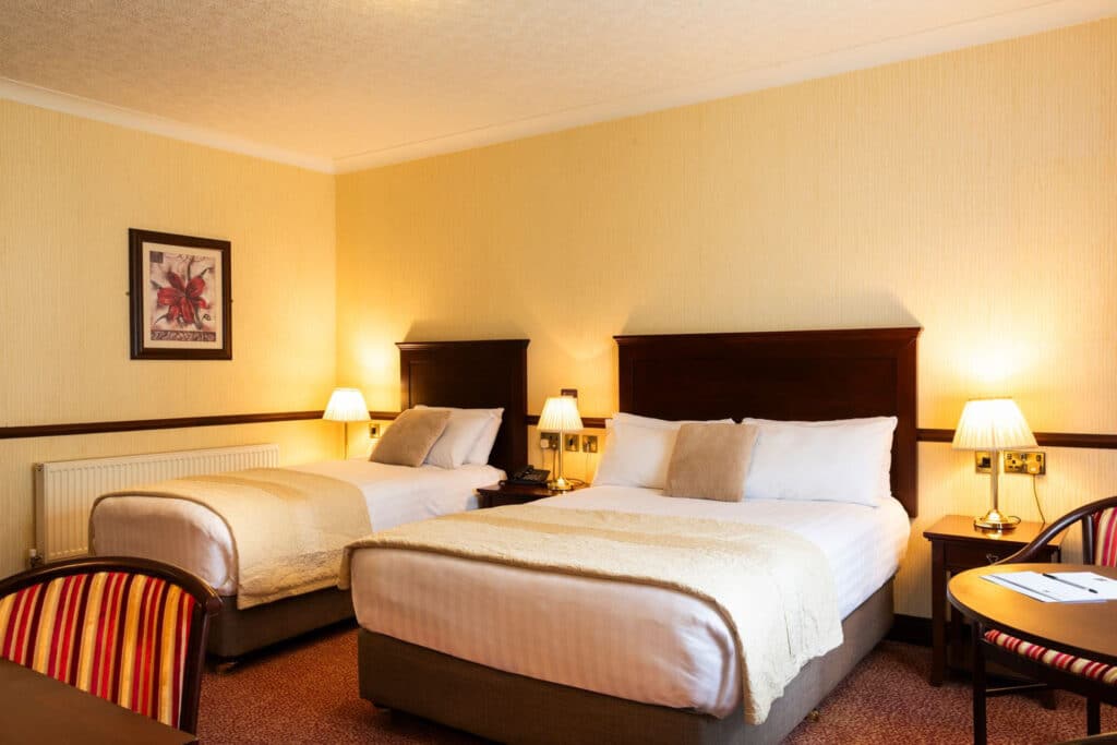 Wide view of double bed and a single bed at Seven Oaks